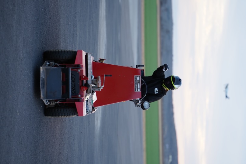 Riding the tarmac tug with helmet on, plane in the background