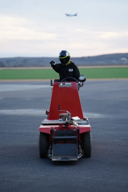 Riding the tarmac tug with helmet on, plane in the background